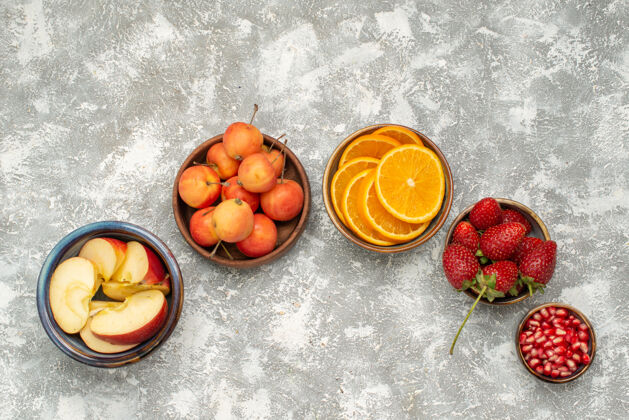 光线顶视图切片水果苹果和橘子与浆果在浅色背景下水果新鲜醇厚维生素健康醇香顶部橙子