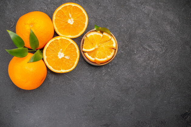 柑橘黑色桌子上一套黄色的整片橙子和切碎的橙子的俯视图果汁减肥切块