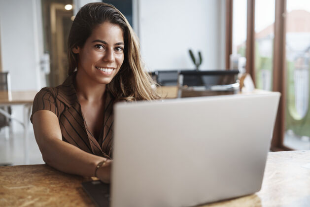员工成功的西班牙女人在咖啡馆用笔记本电脑微笑笔记本电脑桌子工作