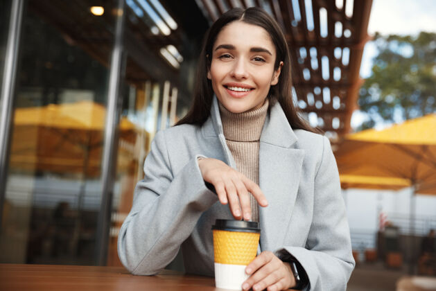 咖啡馆漂亮的年轻女子穿着外套 戴着智能手表在咖啡馆里等着城市微笑年轻