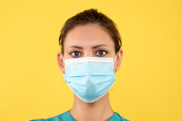 消毒正面近距离观看黄色背景上戴着无菌口罩的女医生医疗肖像视图