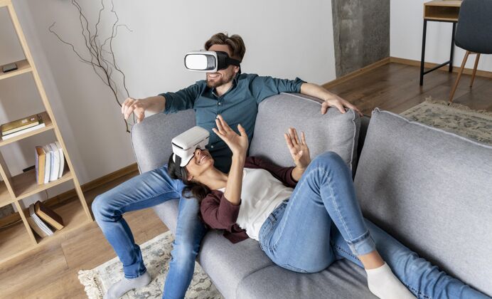 乐趣男人和女人在家里的沙发上与虚拟现实耳机女人水平享受
