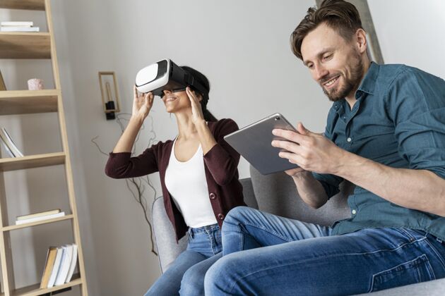 娱乐男人和女人在家里玩虚拟现实耳机和平板电脑虚拟现实眼镜增强现实男性