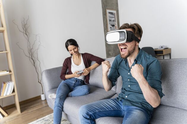 胜利坐在沙发上玩虚拟现实耳机的男人虚拟现实眼镜房子虚拟现实耳机