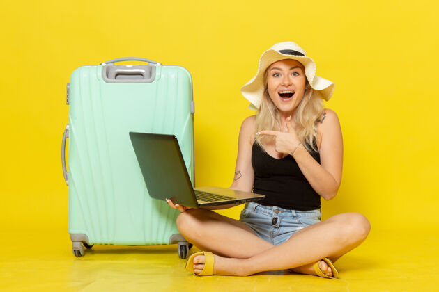 视野前视图年轻女性使用笔记本电脑上的一个黄色的墙壁女孩旅行度假旅行太阳笔记本电脑漂亮成人