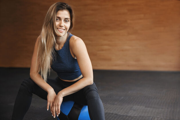 肌肉一个穿着运动服微笑的女运动员坐在健身球的特写镜头微笑健身物理