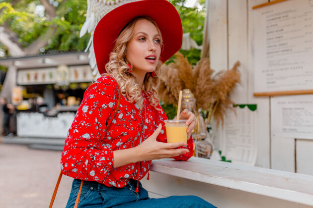 金发迷人时尚的金发微笑女士 头戴草帽 身穿短衫 夏季时尚套装 饮用天然水果鸡尾酒冰沙新鲜持有女人