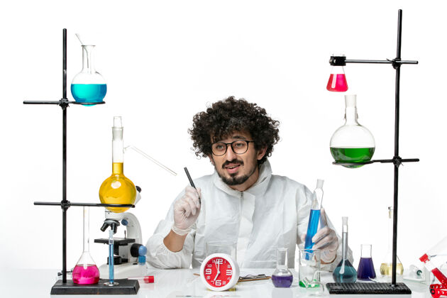 实验正面图身穿白色特别套装的年轻男科学家拿着蓝色溶液 写着笔记烧杯化学罐子