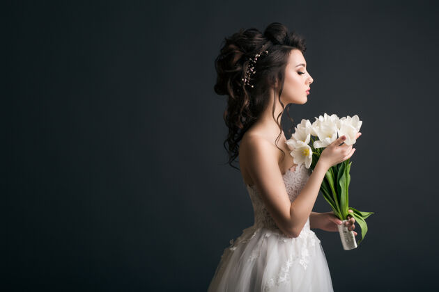 模特穿着婚纱的年轻漂亮时髦的女人快乐花花束