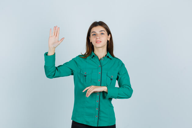 专业身穿绿色衬衫的年轻女士展示手掌 看起来很自信正面视图女性欢呼年轻