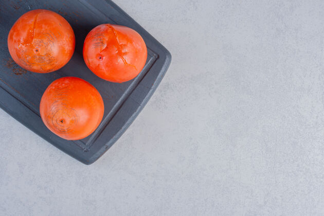 甜点成熟的桔子柿子新鲜的柿子放在木板上特写盘子套餐