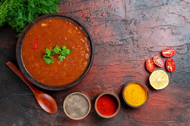 不同经典的番茄汤在一个棕色的碗和不同的香料在混合颜色的桌子上汤碗香料混合