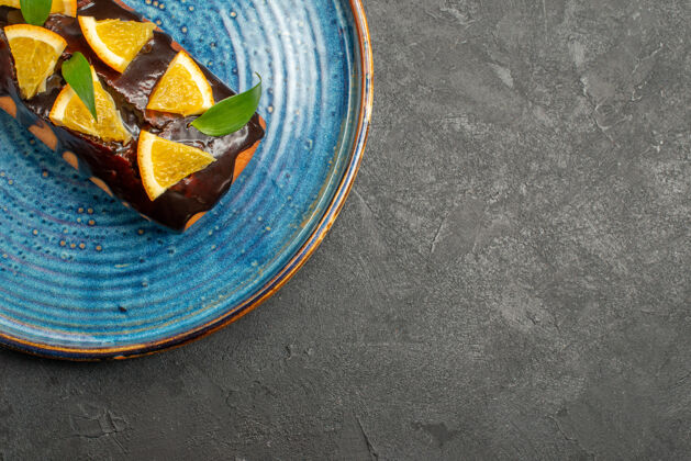 叶黑桌子上放着半张用橘子和巧克力装饰的软蛋糕半巧克力餐