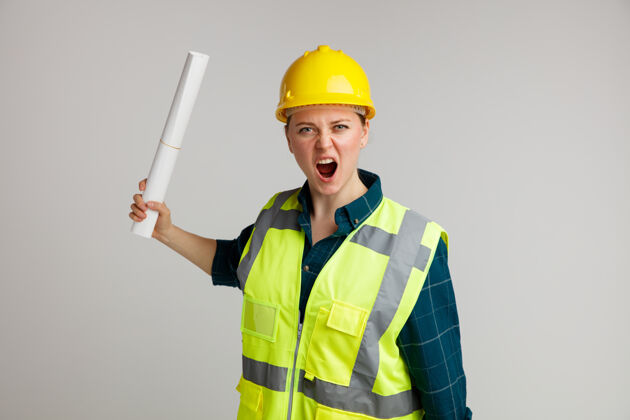 纸愤怒的年轻女建筑工人戴着安全帽和安全背心拿着纸大声喊叫头盔背心白色