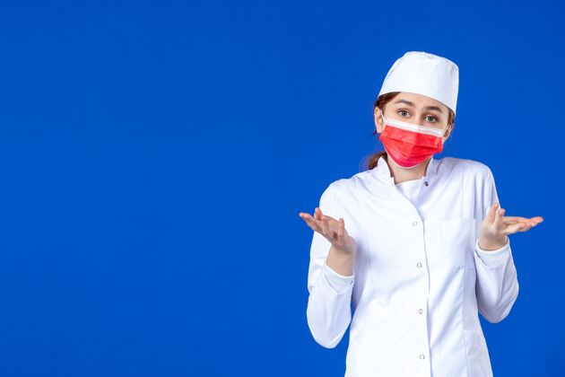 颜色身穿医疗服的年轻护士的正视图 蓝色的面具上有红色的面具医院喜剧演员病毒