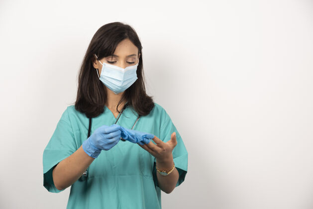 听诊器戴着医用口罩的女医生看着白底手套职业妇女工人
