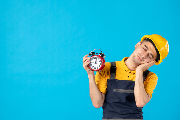 游戏设备穿着黄色制服的疲惫男工人的正视图 蓝色的时钟制服设备时钟