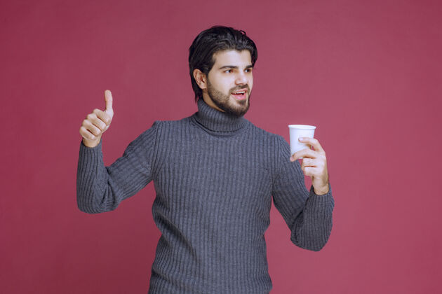 美食男人拿着一个一次性咖啡杯 做着享受的手势语言口味促销