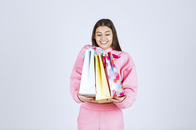 时尚女孩抱着五颜六色的购物袋 感觉很积极雇员年轻人聪明