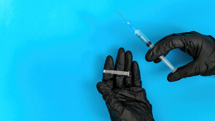 医学手戴黑色医用手套拿着针蓝色背景顶视图注射器药物大流行