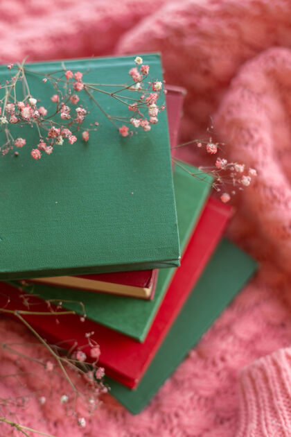 花一堆红绿相间的书 粉色温暖的针织毛衣上挂着干花故事编织春天的心情