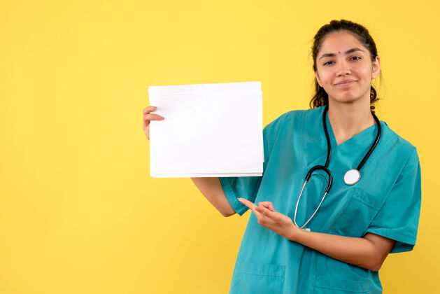 纸张正面图幸福女医生指着黄色背景的文件医学护士背景