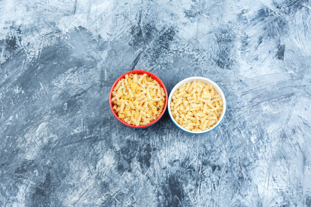 通心粉各种各样的意大利面放在碗里 背景是灰泥平铺晚餐食物碳水化合物