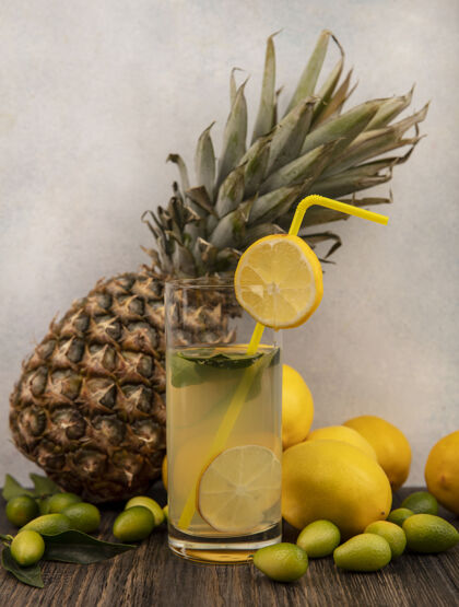 丰富侧视图丰富的维生素柠檬汁在一个玻璃与菠萝柠檬和金盏花隔离在一个白色表面的木桌上玻璃果汁餐桌