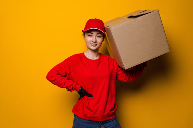 分销年轻的亚洲妇女抱着一个纸板箱 背着一个黄色的隔离购买互联网快递