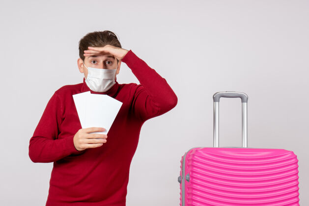 成人白墙上戴着面具拿着飞机票的年轻男子的正视图举行假日流行病