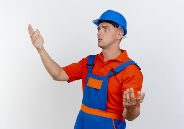 男人看着身边迷茫的年轻男建筑工人穿着制服 戴着安全帽假装拿着什么东西制服穿头盔