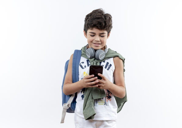 孩子高兴的小男生戴着背包和耳机拨号码小学生耳机学生