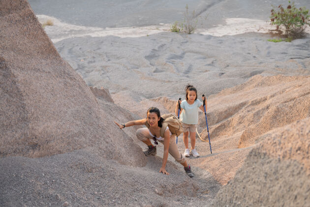 自然家庭旅游-徒步旅行者背着背包看山景 母亲带着孩子在白天人一起活动