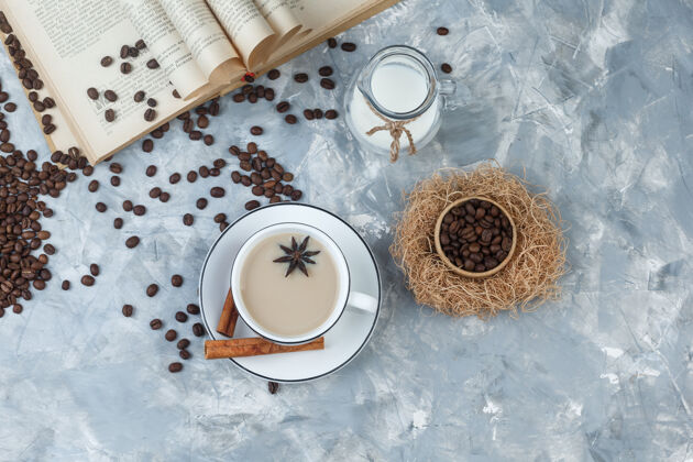 早晨一套咖啡豆 书 牛奶 香料和咖啡在一个灰色的石膏背景杯顶视图笑乐趣香料