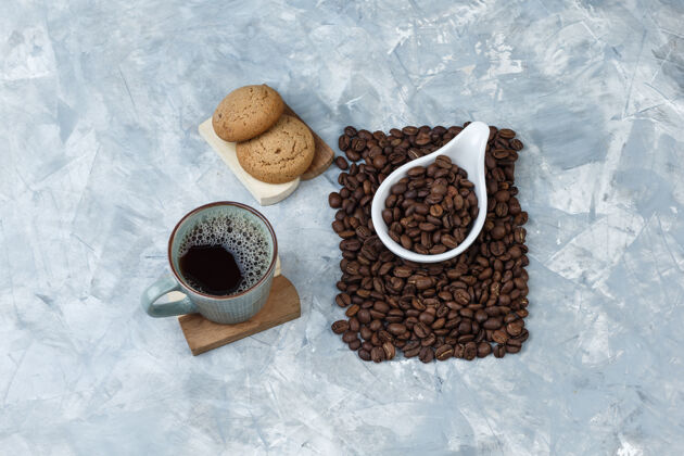 木板砧板上的一套饼干 白瓷壶里的一杯咖啡和咖啡豆烤乡村的味道