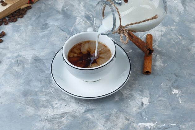 高角度观看倒入牛奶的咖啡杯 咖啡豆 肉桂棒的灰色背景水平早餐卡布奇诺意式浓缩咖啡