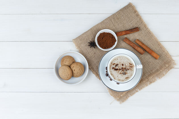 曲奇一套咖啡豆 磨碎的咖啡 香料 饼干和咖啡在一个木杯和一块布袋背景顶视图粗麻布自然拿铁