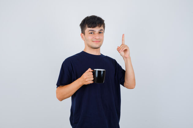 男性年轻人手里拿着一杯茶 指着头 穿着黑色t恤 看上去很自信正面图成功休闲男人