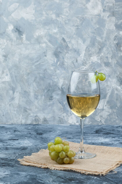 成熟侧视图绿色葡萄与一杯葡萄酒的垃圾和一块布袋背景垂直自然玻璃夏天