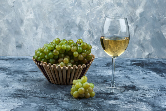 美味一套葡萄酒和绿色葡萄在一个肮脏的石膏背景篮子侧视图组成新鲜玻璃