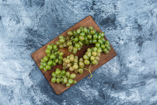 果汁把白葡萄平放在深蓝色大理石背景的砧板上水平切割串营养