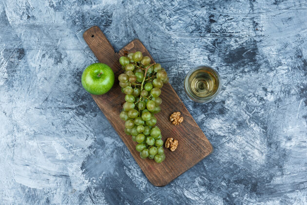 多汁的俯视图：白葡萄 核桃 苹果放在砧板上 一杯威士忌放在深蓝色大理石背景上水平秋天浆果苹果