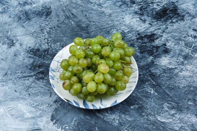 藤蔓绿色葡萄在一个肮脏的石膏背景板高角度的看法自然葡萄酒树枝