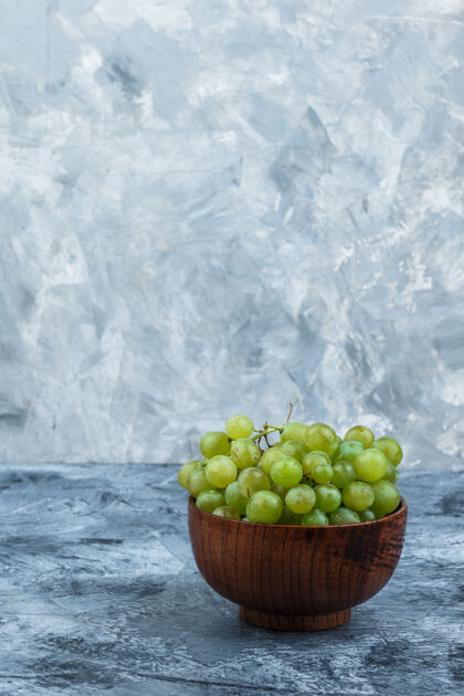 葡萄把碗里的白葡萄放在深蓝色和浅蓝色的大理石背景上垂直葡萄浆果大理石
