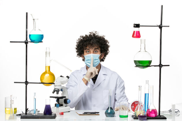 男性化学家正面图：男药剂师穿着医疗服 戴着口罩 坐在不同的溶液中 在空白处摆姿势解决方案化学面具
