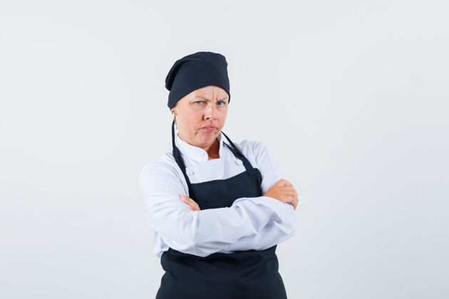 亚洲身着制服的女厨师 围裙交叉双臂站着 看起来很生气 正面视图清洁皮肤护理黑发