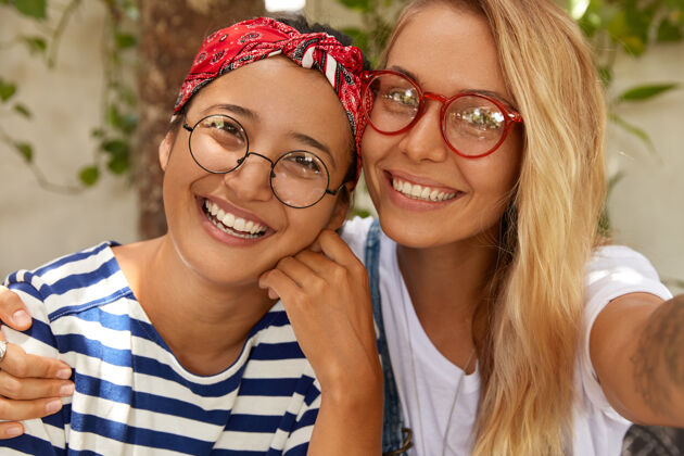 同伴混血友好的特写镜头两个女孩摆出自拍姿势 展现异族友谊桌子眼镜牙齿