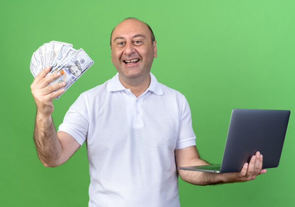 休闲微笑休闲的成熟男子拿着现金和笔记本电脑隔离在绿墙上成熟持有男人