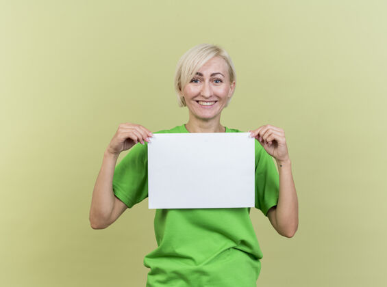 斯拉夫人快乐的中年金发斯拉夫女人拿着空白纸隔离在橄榄绿的墙上橄榄金发女人