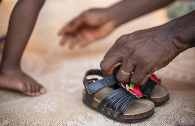 孩子爸爸在帮他的女婴穿鞋子年轻非洲黑人女孩
